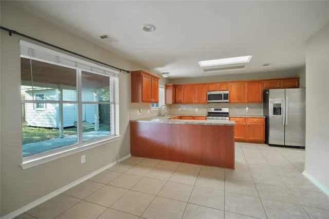 a large kitchen with stainless steel appliances granite countertop a large counter top and a refrigerator
