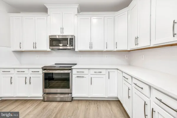 a kitchen with stainless steel appliances granite countertop a stove a microwave and white cabinets
