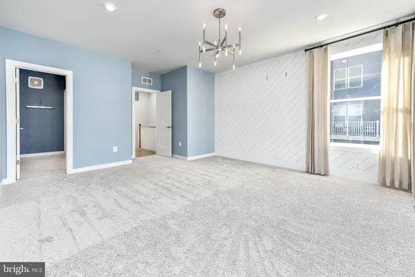 a view of a big room with a chandelier fan and windows