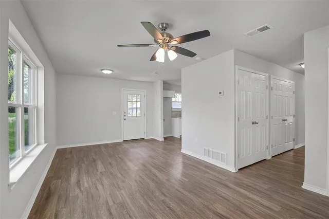 a view of an empty room with wooden floor and window