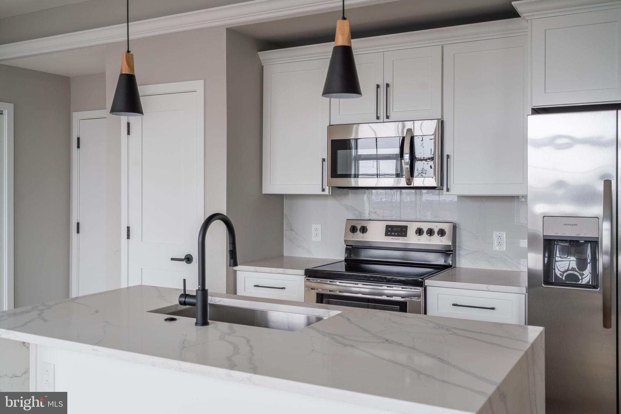 2401 Washington Avenue, Unit 5D Philadelphia, PA 19146 - Photo 2 of 18 a kitchen with stainless steel appliances a sink a stove and a wooden floors
