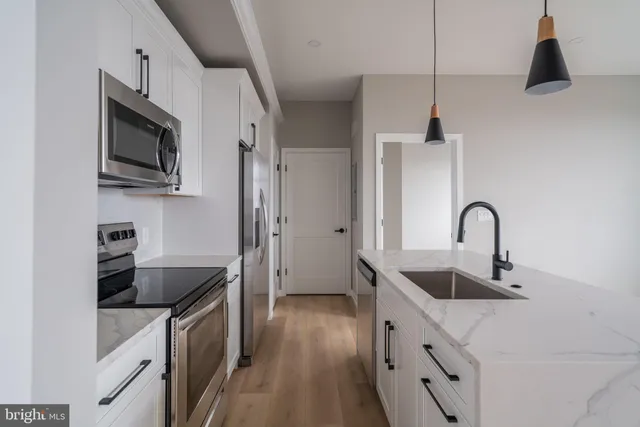 a kitchen with stainless steel appliances granite countertop a sink a stove and a refrigerator