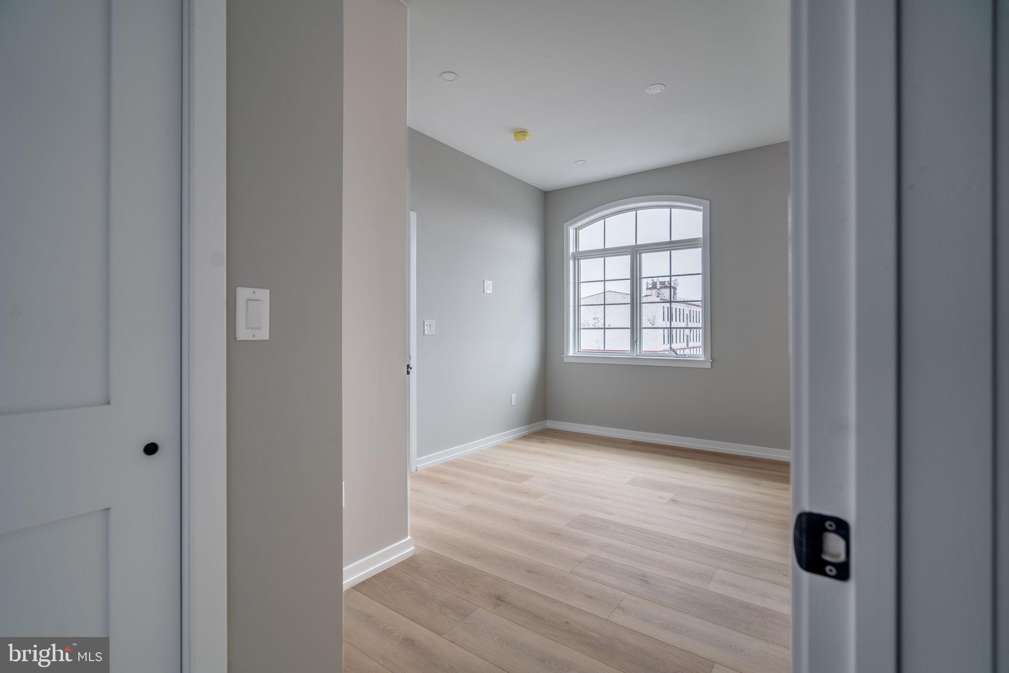 2401 Washington Avenue, Unit 5D Philadelphia, PA 19146 - Photo 8 of 18 a view of an empty room with wooden floor and a window