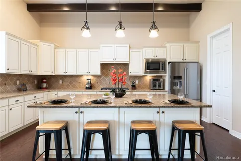 a kitchen with stainless steel appliances granite countertop a dining table chairs refrigerator and microwave