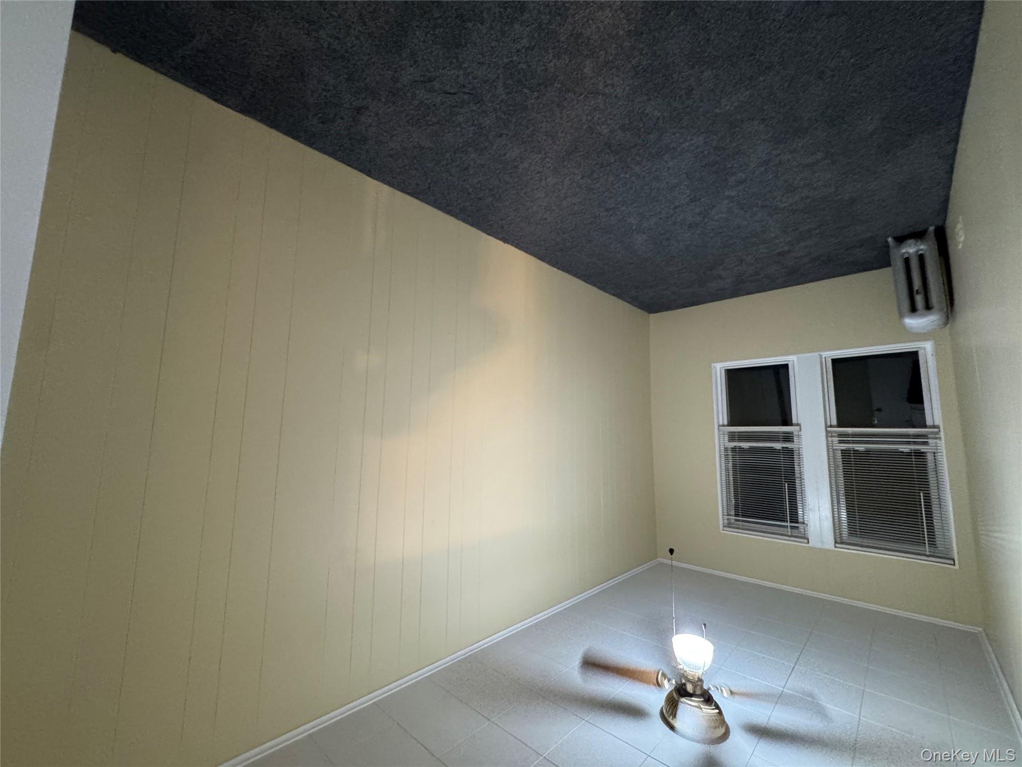 40-13 201st Street Queens, NY 11361 - Photo 11 of 16 an empty room with windows and fan