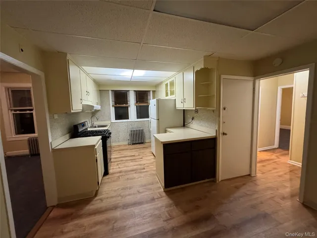 a living room with stainless steel appliances kitchen island granite countertop a refrigerator a sink dishwasher and a stove with wooden floor