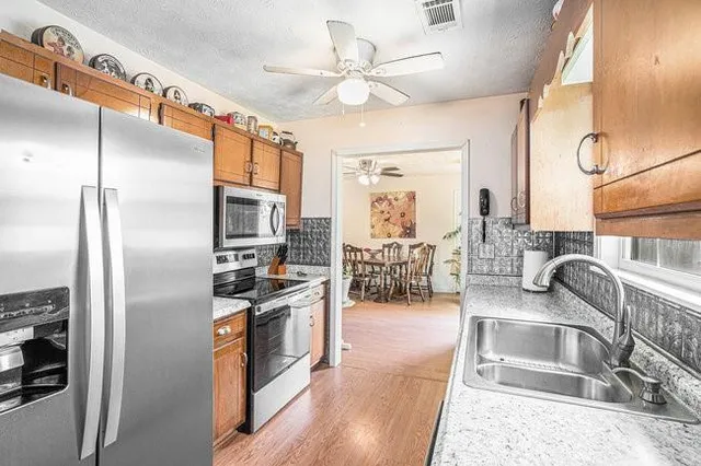 a kitchen with stainless steel appliances granite countertop a refrigerator a stove and a sink with couches