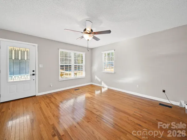 a view of an empty room with wooden floor and a window