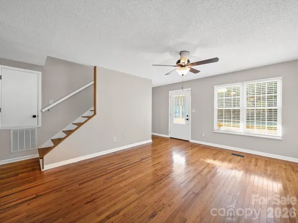 a view of an room with wooden floor ceiling fan and windows