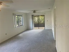 a view of a big room with windows and chandelier fan
