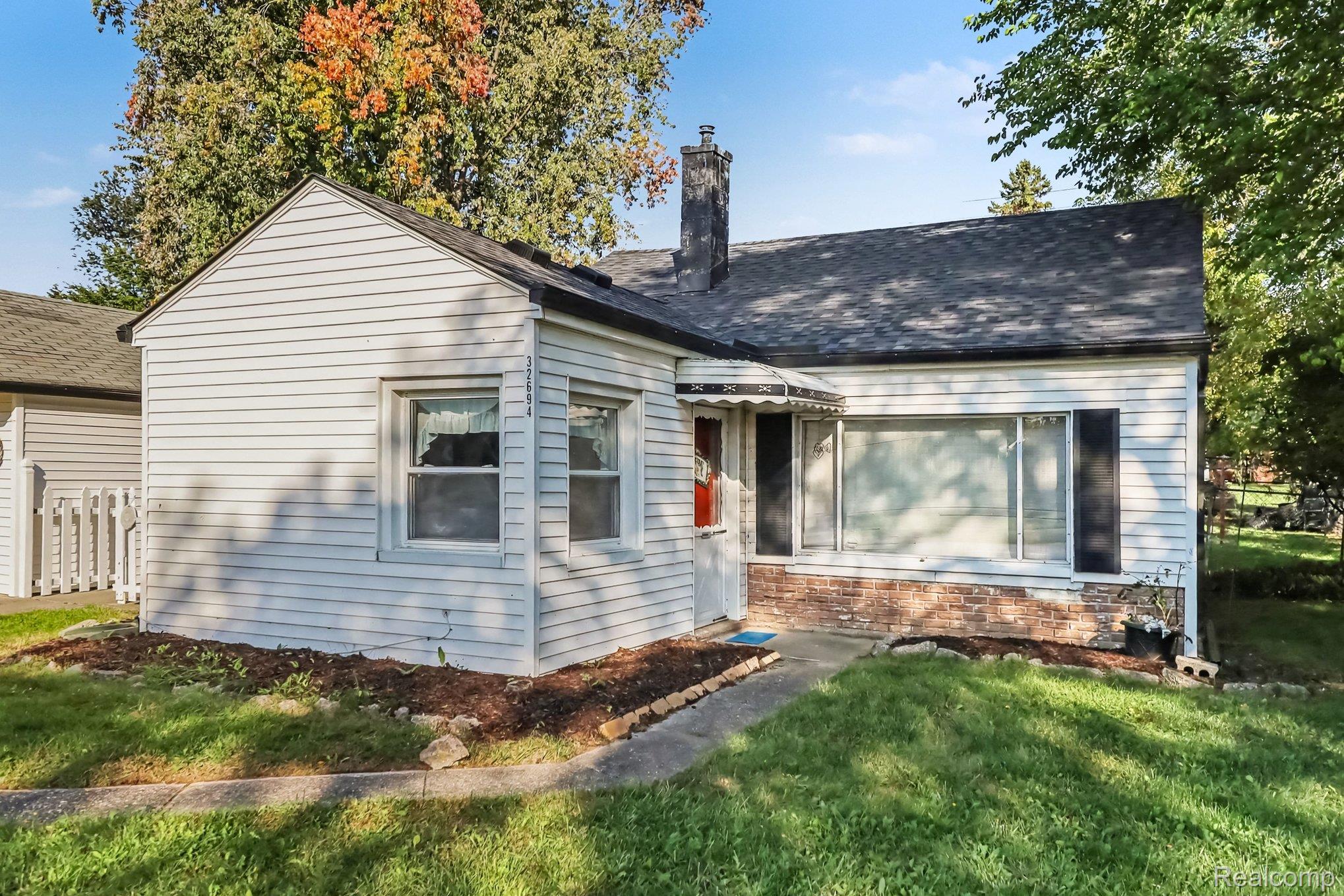 32694 Ruehle Avenue Warren, MI 48093 - Photo 1 of 15 Charming ranch-style home featuring white horizontal siding, a brick chimney, and a gabled roofline
