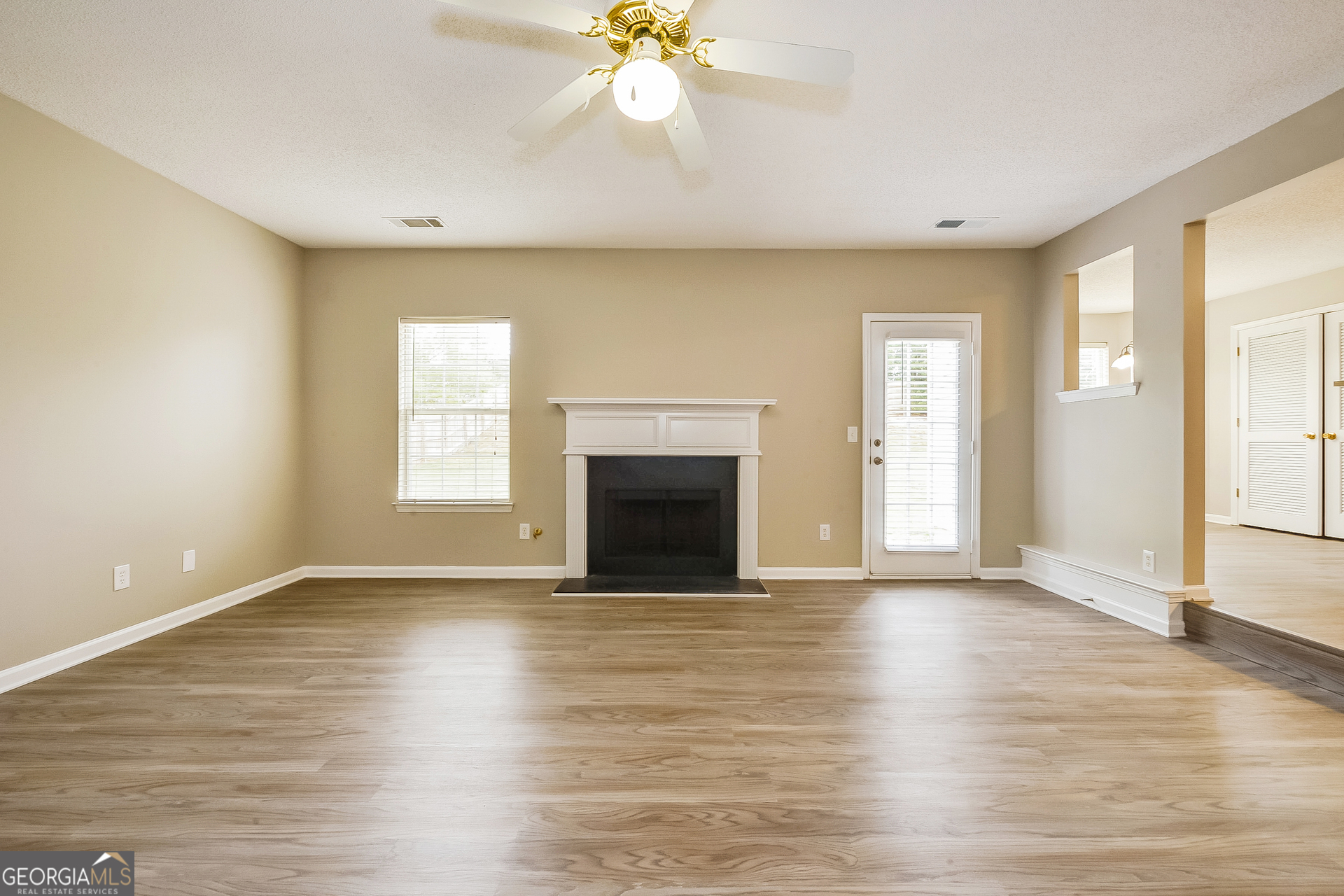 1707 Deer Crossing Way Jonesboro, GA 30236 - Photo 7 of 17 an empty room with wooden floor fireplace and windows