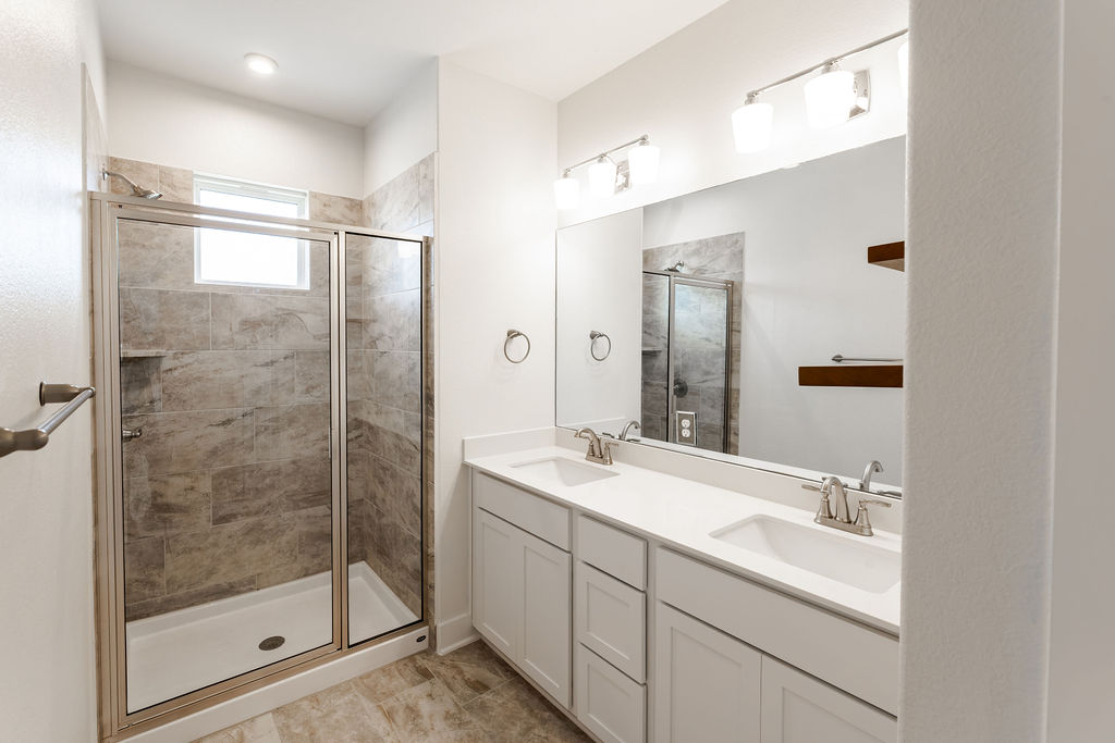 6414 Cowman Way Austin, TX 78747 - Photo 21 of 35 A spacious double vanity and custom-tiled walk-in shower define this contemporary bathroom.