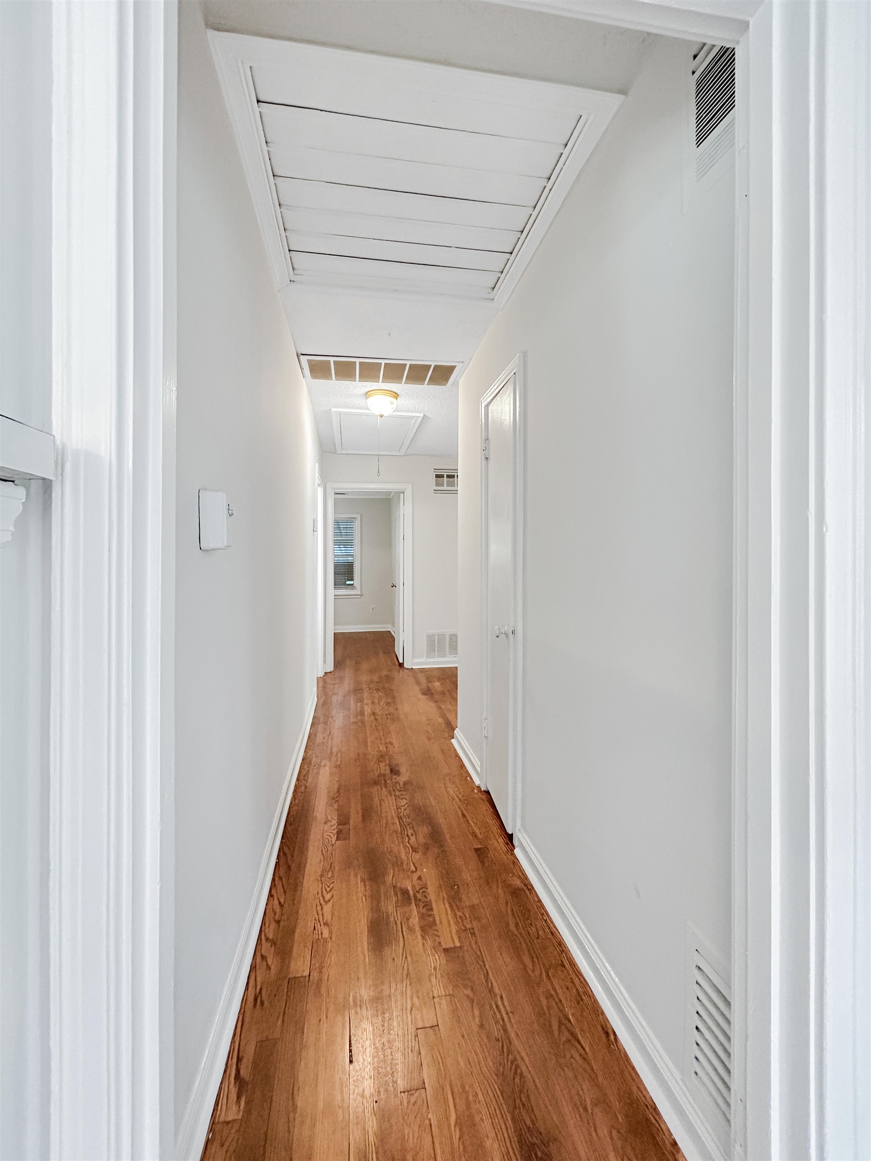 813 Moss Road Memphis, TN 38117 - Photo 8 of 16 Hardwood flooring extends throughout this hallway, featuring crisp white walls and baseboards