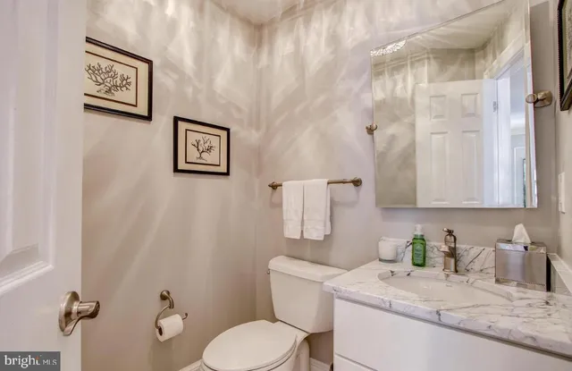 a bathroom with a granite countertop sink mirror vanity and toilet