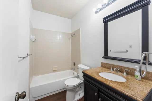 a bathroom with a granite countertop sink a toilet a mirror and bathtub