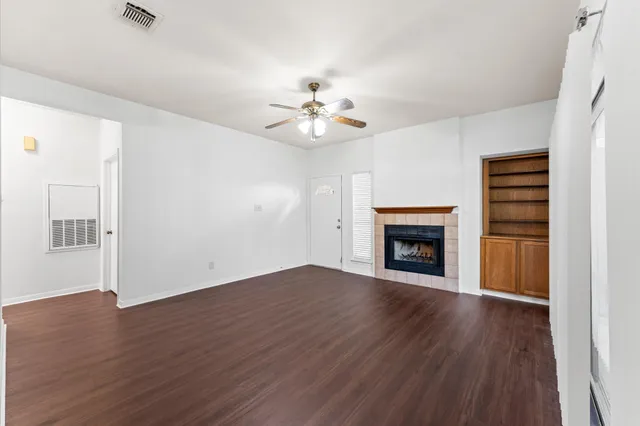 a view of an empty room with wooden floor fireplace and a window