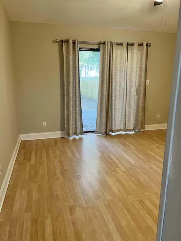 an empty room with wooden floor and a bathroom
