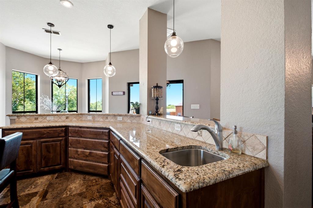 600 Aspen Street Pilot Point, TX 76258 - Photo 20 of 39 Kitchen space featuring wood cabinetry, granite countertops, an undermount stainless steel sink, and a tiled backsplash