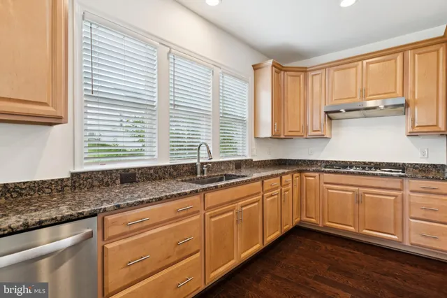 a kitchen with granite countertop stainless steel appliances a sink and cabinets