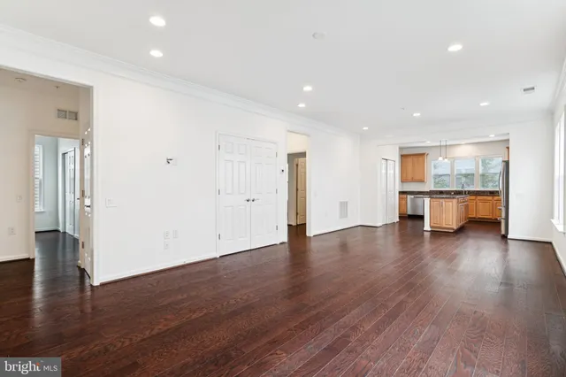 a view of empty room with wooden floor and kitchen view