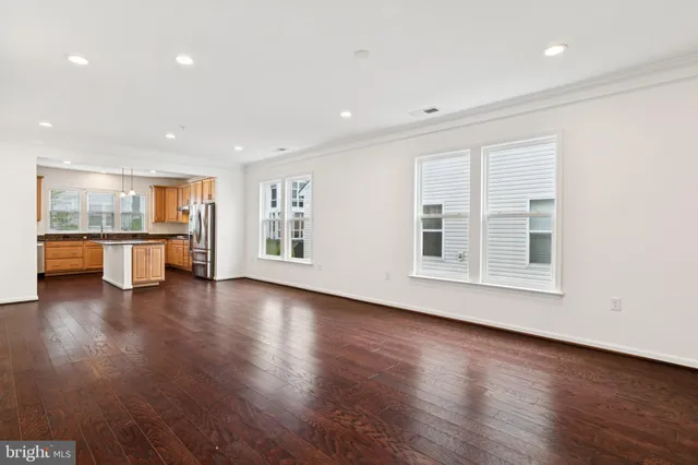 a view of empty room with wooden floor and kitchen