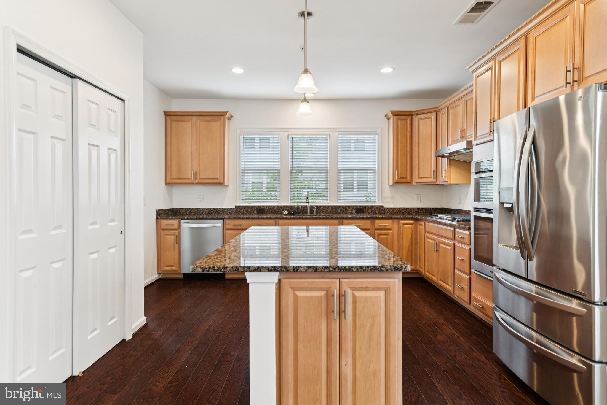 15 Point Bluff Street Fredericksburg, VA 22406 - Photo 9 of 25 a kitchen with stainless steel appliances granite countertop a refrigerator a sink dishwasher a stove and white countertops with wooden floor