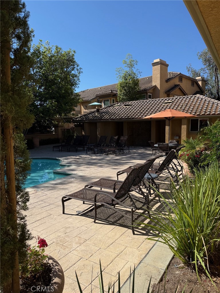 19431 Rue De Valore, Unit 14A Lake Forest, CA 92610 - Photo 20 of 26 a view of a patio with table and chairs under an umbrella with large trees