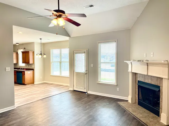a view of an empty room with kitchen and fireplace