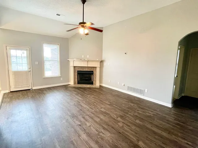 a view of an empty room with wooden floor fireplace and a window