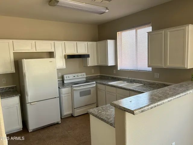 a kitchen with granite countertop white cabinets and white appliances