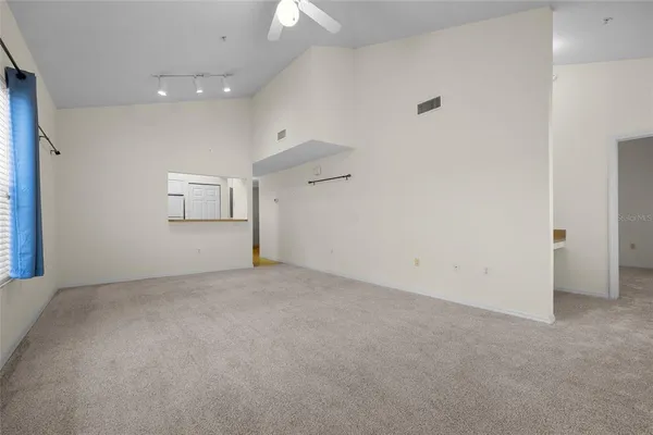 an empty room with chandelier fan and windows