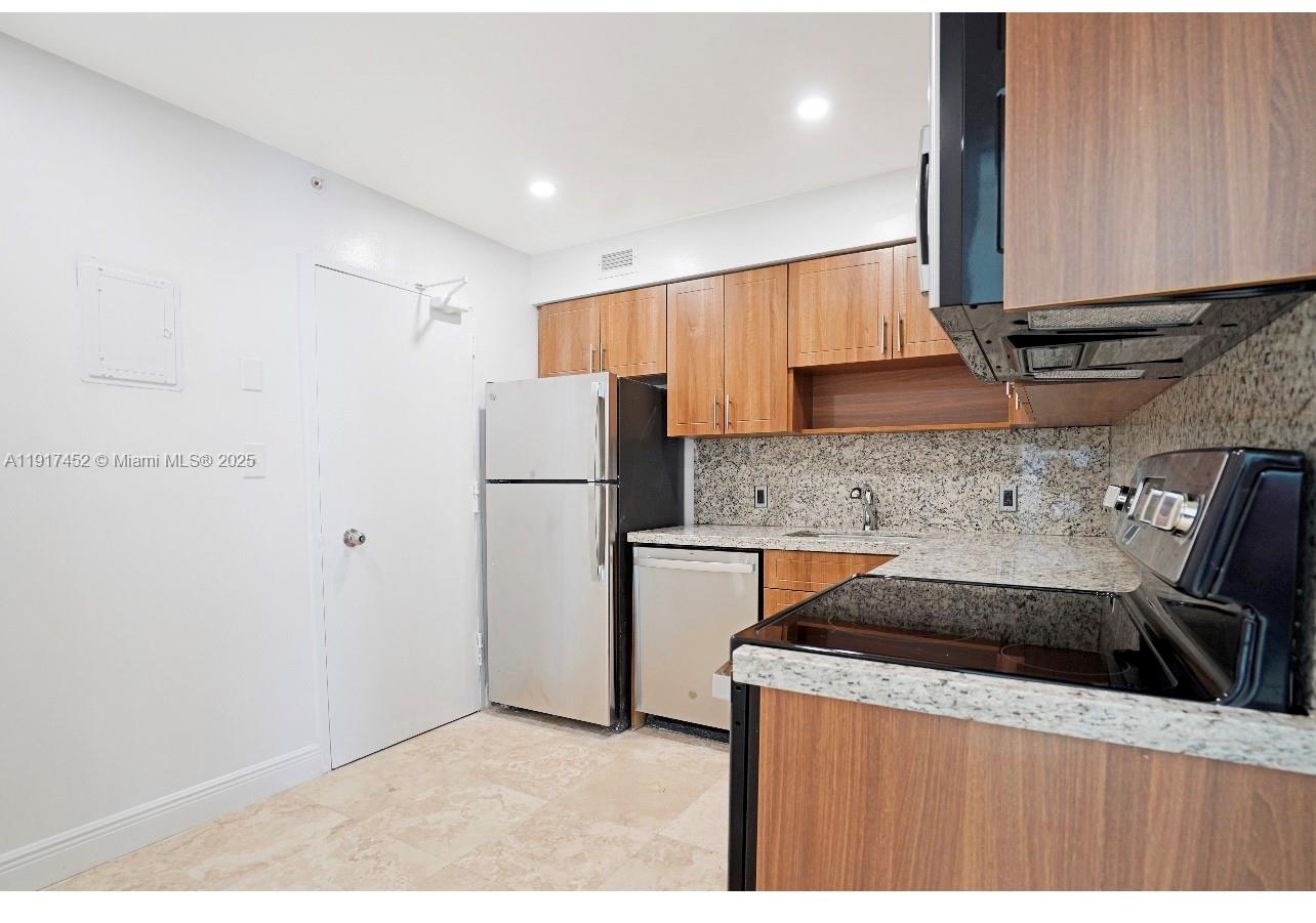 5101 Collins Avenue, Unit 14J Miami Beach, FL 33140 - Photo 3 of 10 a kitchen with a refrigerator sink and cabinets