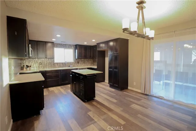 a kitchen with stainless steel appliances granite countertop a refrigerator a sink dishwasher a stove and white countertops with wooden floor