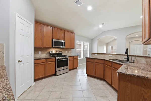 a large kitchen with granite countertop stainless steel appliances and a sink