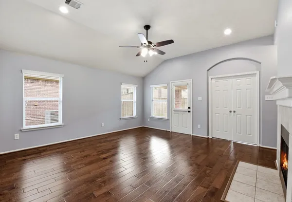 a view of an empty room with window and wooden floor