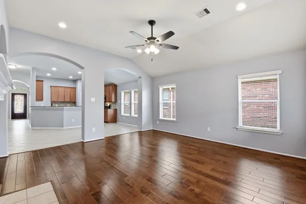 a view of an empty room with wooden floor and a window