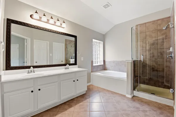 a bathroom with a tub a double vanity sink and mirror