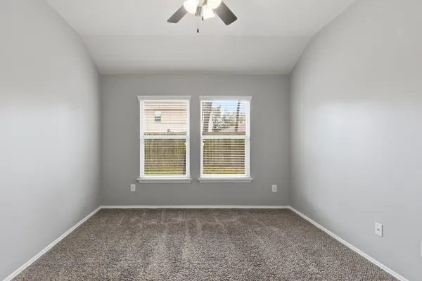 an empty room with a window and a fan