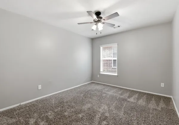 a view of an empty room with chandelier fan