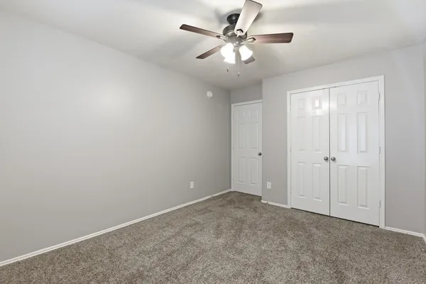 an empty room with a ceiling fan and a window
