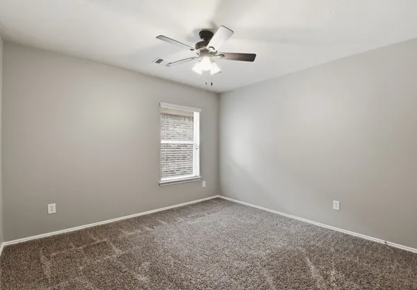 an empty room with window and ceiling fan