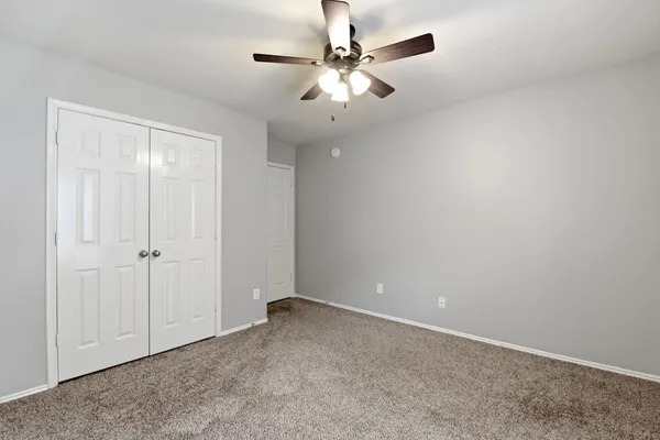 an empty room with a ceiling fan and a window