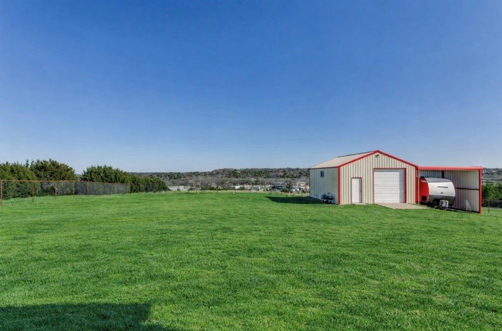259 Hidden Creek Road Cresson, TX 76035 - Photo 24 of 28 View of grassy yard with an outbuilding, a detached garage, and oil tank