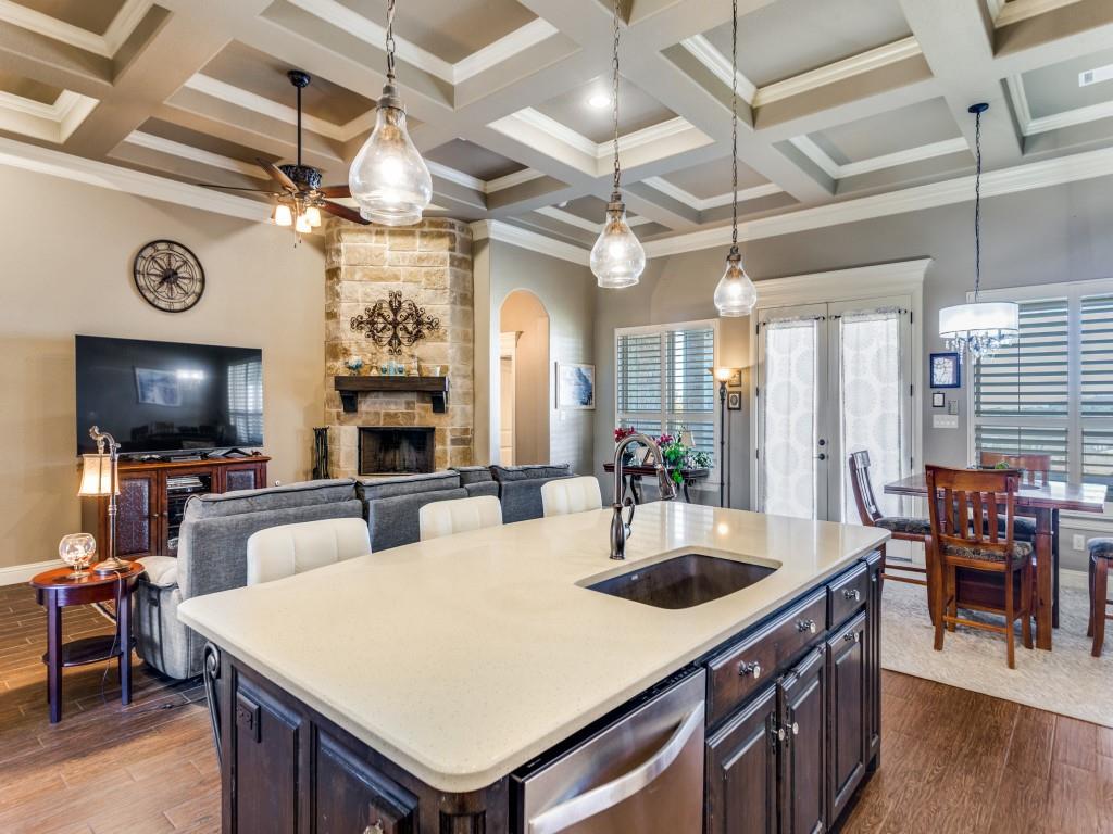 259 Hidden Creek Road Cresson, TX 76035 - Photo 10 of 28 Kitchen featuring hanging light fixtures, dark wood-type flooring, dark wood finish cabinets, a stone fireplace, and crown molding