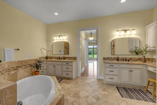a spacious bathroom with a double vanity sink a mirror and a bathtub