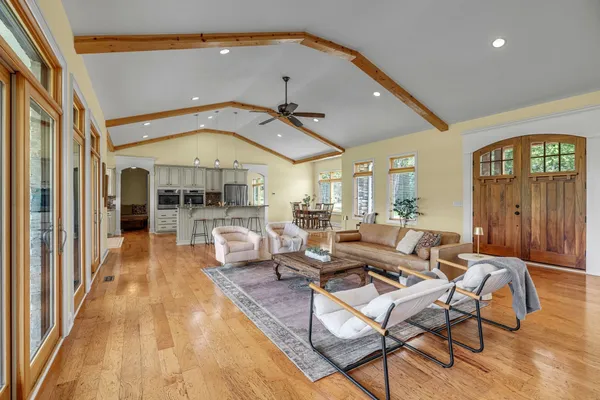 a living room with furniture large windows and wooden floor