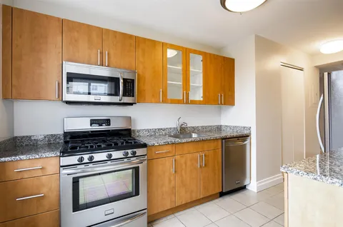 a kitchen with stainless steel appliances granite countertop a stove microwave refrigerator and sink