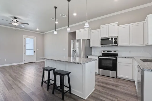 a kitchen with stainless steel appliances a kitchen island hardwood floor sink stove dining table and chairs