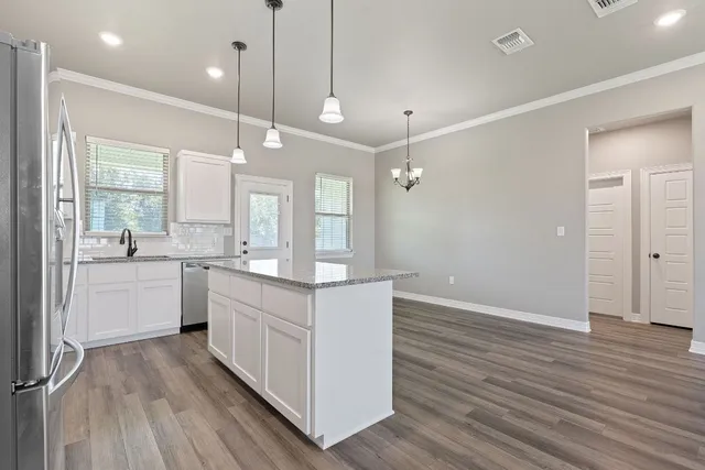 a large white kitchen with a sink a refrigerator and window